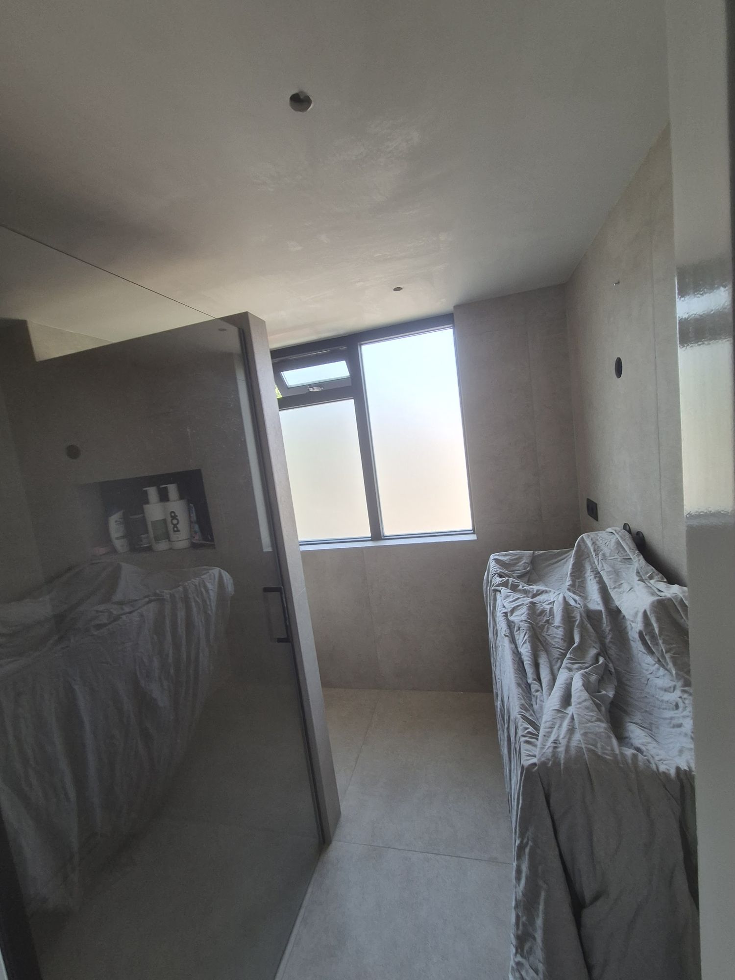 Een betegelde badkamer met een glad gestuct plafond